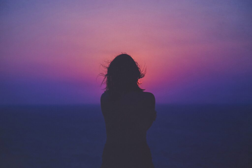 silhouette of woman with pink and purple sky